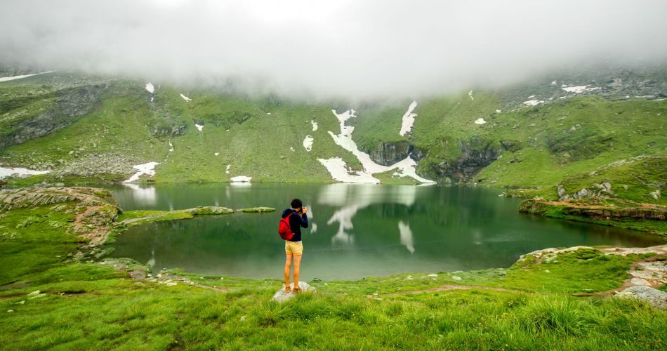 Photographer with backpack standing on Balea lake.